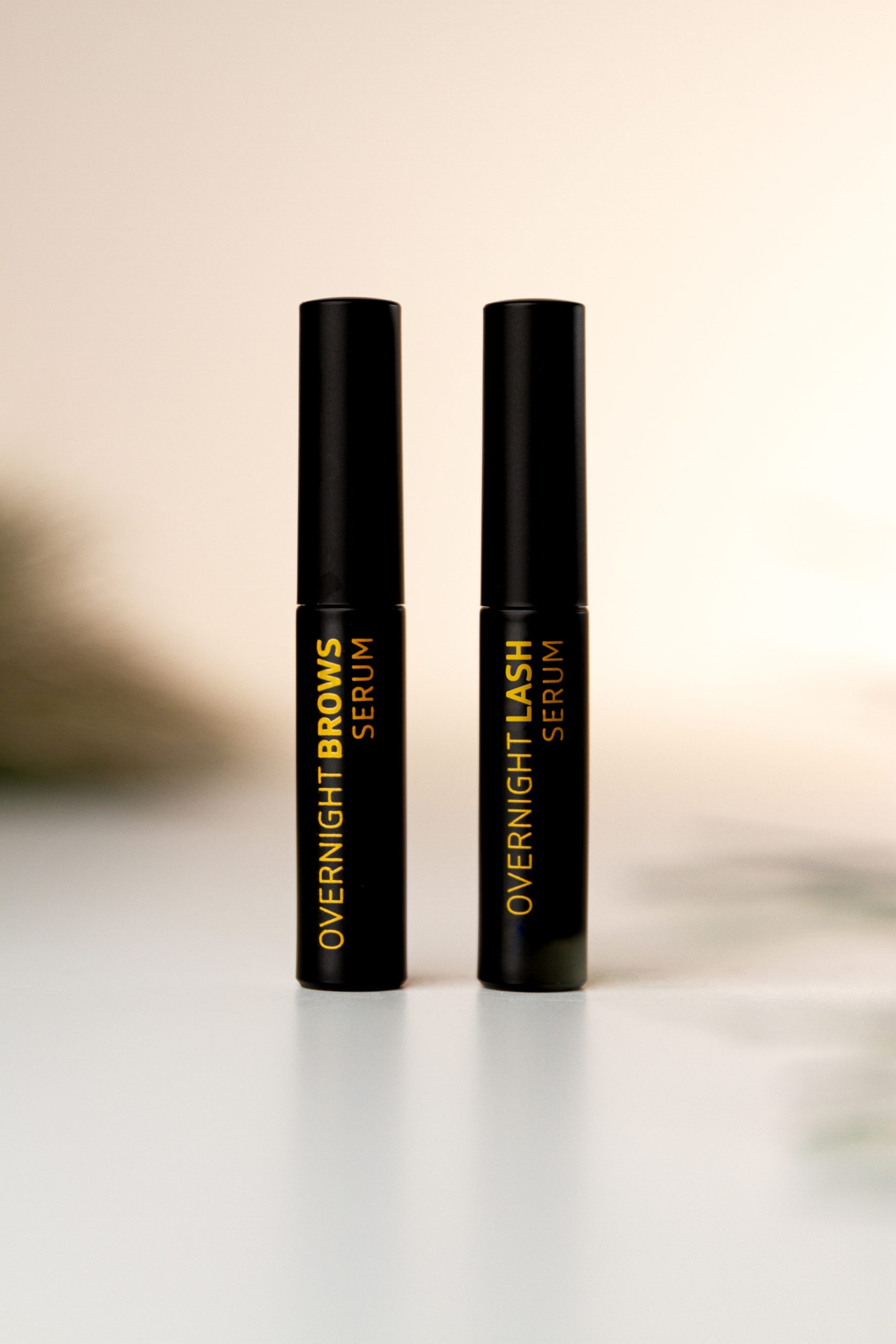 Two black lip balm tubes on a white surface.